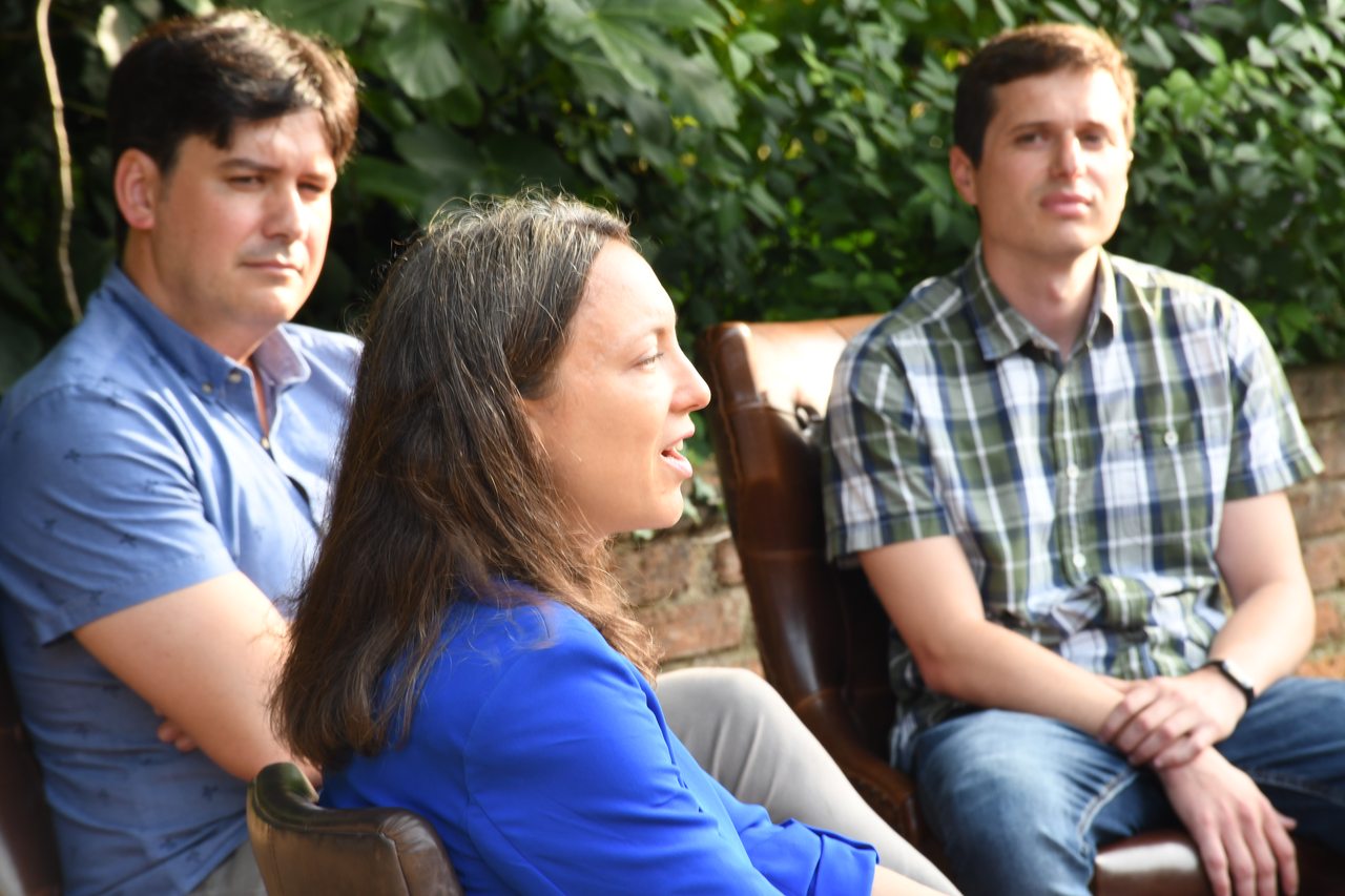 Three participants listen to a discussion outdoors at Diáspora