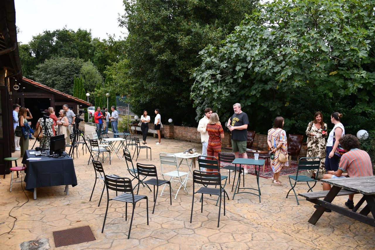 People gather around tables in the courtyard at Diáspora