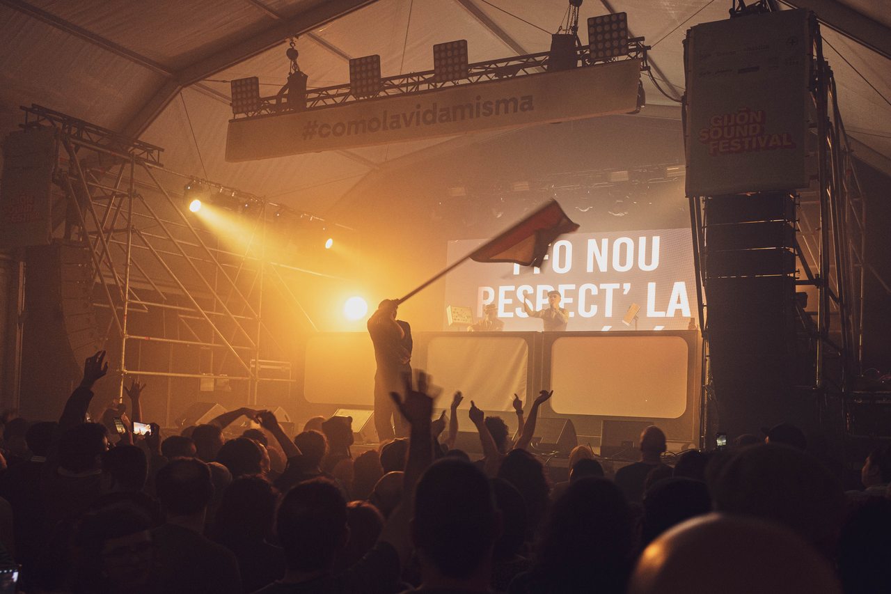 An audience faces a stage filled with amber light at Gijón Sound Festival